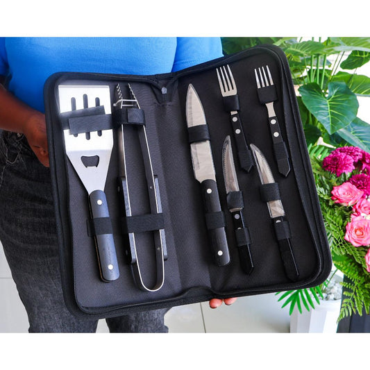 A 7-piece barbecue tool set with stainless steel blades and black handles, displayed inside an open black zippered carrying case. The set includes a spatula, tongs, three knives, and two forks.