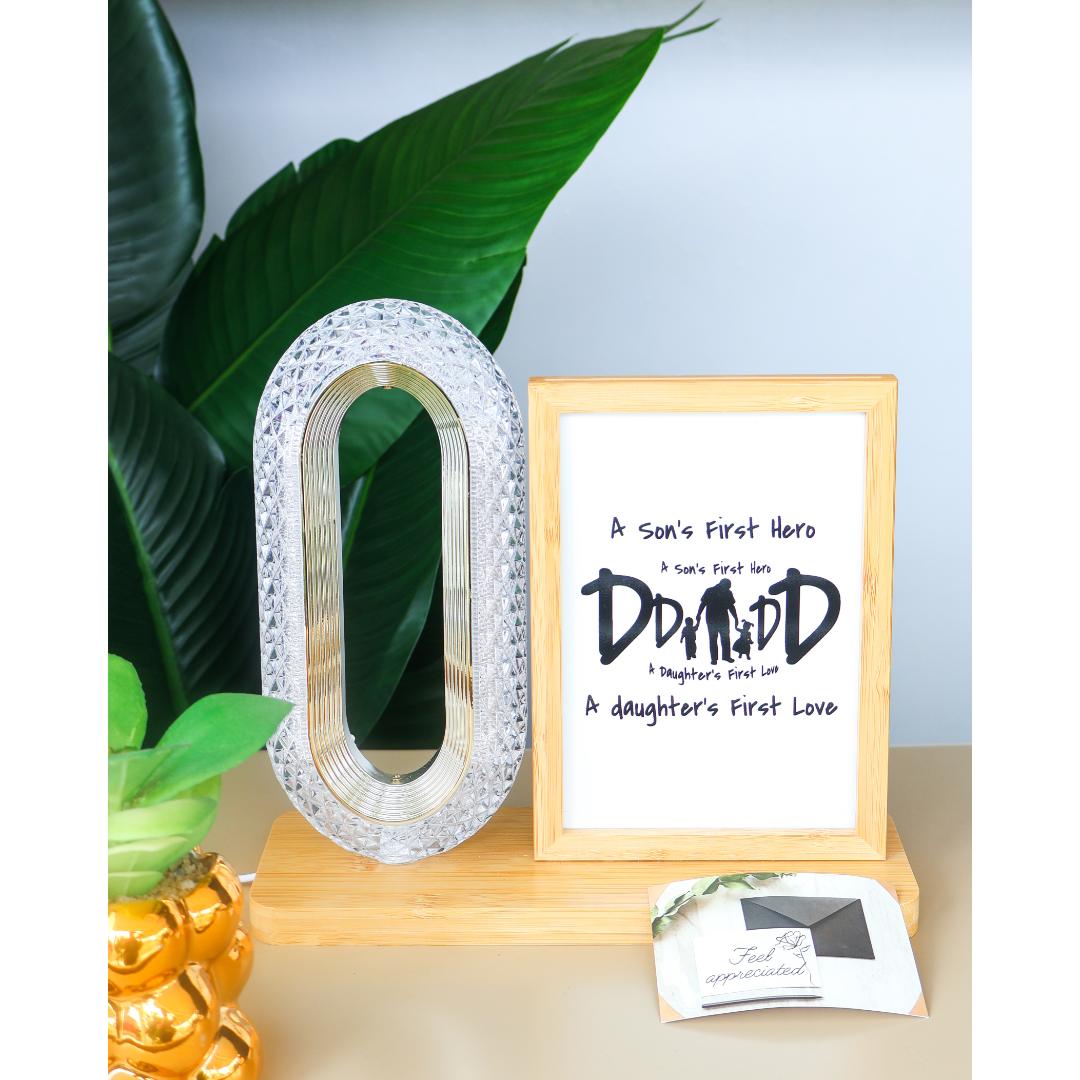 A framed personalized office desk display featuring a crystal oval ring lamp and a matching wooden picture frame displaying a beautiful typographic print that celebrates Dad.