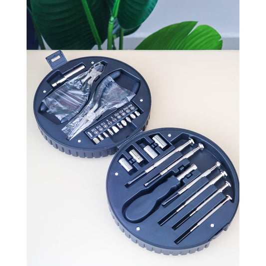 A circular screwdriver set in a dark navy case containing multiple precision screwdrivers, small bits, and a plastic bag of accessories.