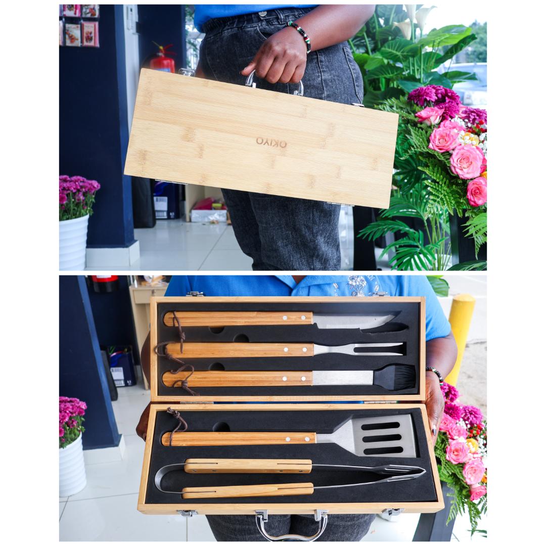 A bamboo BBQ tool set in a wooden carrying case displaying stainless steel tools with bamboo handles.